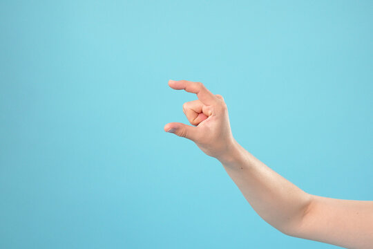 Hand Showing Small Measurement or Pinch Gesture Against Blue Background