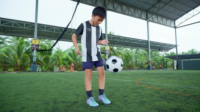 Close-up of a boy kicking a soccer ball on a green turf field, with sharp detail and frozen motion, representing youth sports, training, fitness and a healthy active lifestyle.