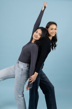 Two Playful Young Women Posing Together On Blue Background