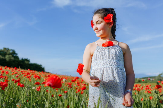 Young Girl Smiling with Red Poppies in a Flower Field, Summer Portrait