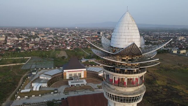 Aerial view of the Menara Pandang Teratai tower with its distinctive lotus-shaped top, overlooking the urban landscape of Purwokerto, Central Java, Indonesia.