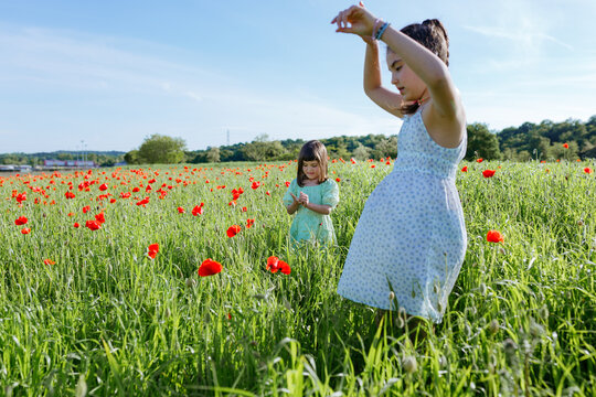 Two Sisters Playing Together in a Field of Red Poppies
