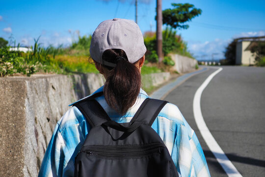 田園風景の中を歩く人の後ろ姿
