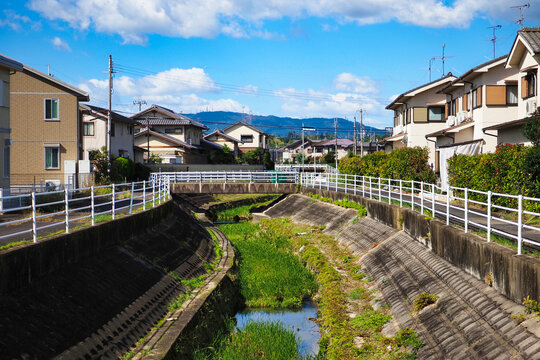 住宅街の中を流れる小さな川と橋、晴れた日の風景