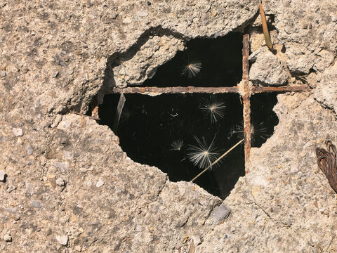 Broken concrete slab with a hole exposing rusty rebar infrastructure