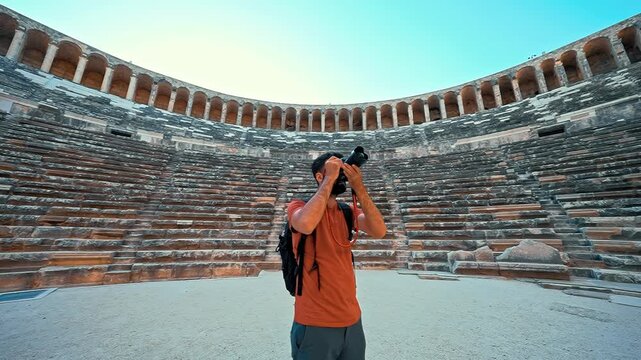 Aspendos, Antalya features an ancient Roman amphitheater where a young photographer films with his camera among historic ruins.