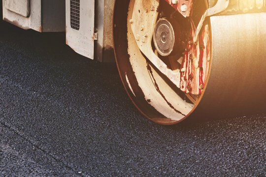 Industrial Road Roller Presses Fresh Dark Asphalt on a City Street During Daytime Work
