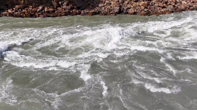 Fast flowing muddy river rapids with turbulent white water churning