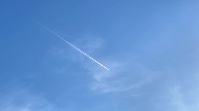 An airplane flies at high altitude across a clear blue sky leaving a long white contrail, suitable for airline advertising, travel marketing, and aerospace media.