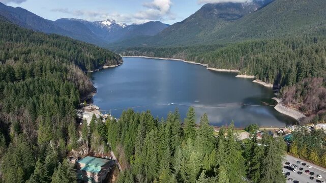 Capilano Reservoir Bordered By Lush Pine Forest And Mountain Peaks In North Vancouver, British Columbia, Canada. - aerial shot