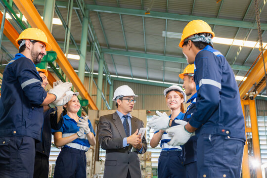 Successful engineering team and manager celebrating success with applause in manufacturing plant, Diverse group of factory engineers and manager clapping hands during meeting in industrial factory