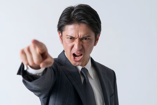 怒鳴る日本人ビジネスマンが指をさす様子