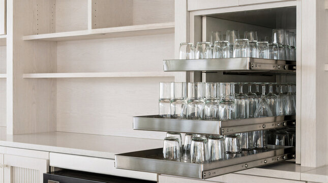 Twin pullout caddy towers in whitewashed oak behind a cafe counter carrying tiered stainless caddies of glassware