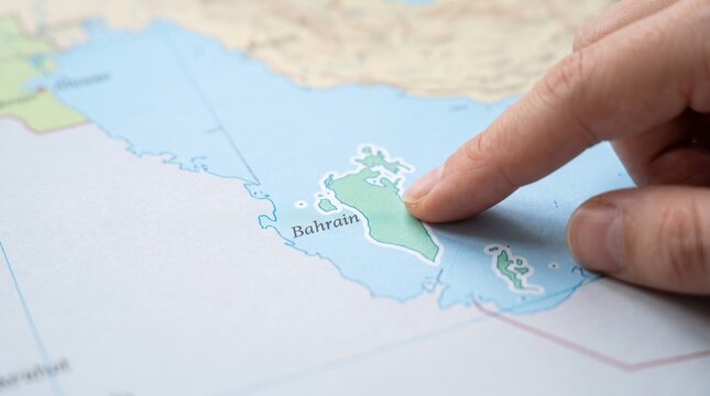 A person's finger pointing to Bahrain on a geographical map
