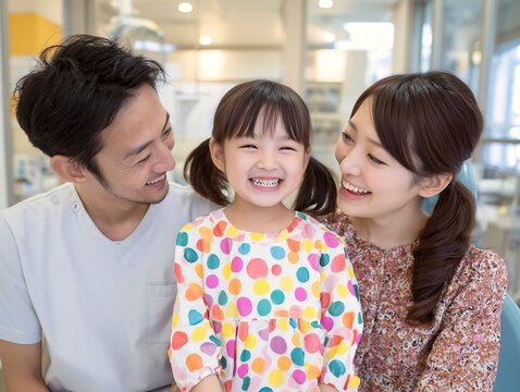歯科クリニックで診察を終えた女の子が両親に囲まれて安心して笑顔を見せる家族