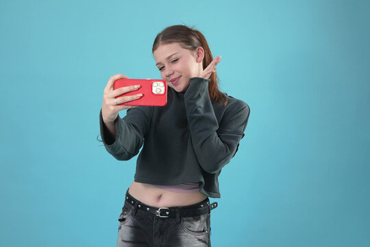 Young Woman Smiling and Posing for Selfie with Red Smartphone