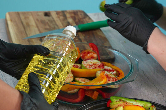Chef Pouring Vegetable Oil onto Seasoned Peppers and Zucchini
