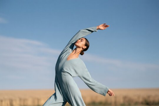 Contemporary dance portrait of a woman in a flowing blue jumpsuit in a golden field for fashion background and banner design