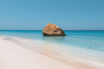 View of a large rock formation in the turquoise waters of the Arher Campsite beach with white sand and clear blue sky in Socotra, Yemen. © Travel 'n' Lifestyle