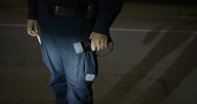 A police officer is working on the street with a breathalyzer