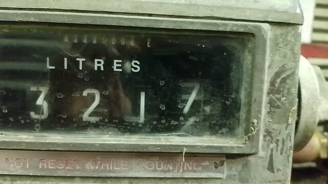 Close-up shot of a vintage fuel pump analog counter displaying volume measurement in litres on a gas station dispenser.