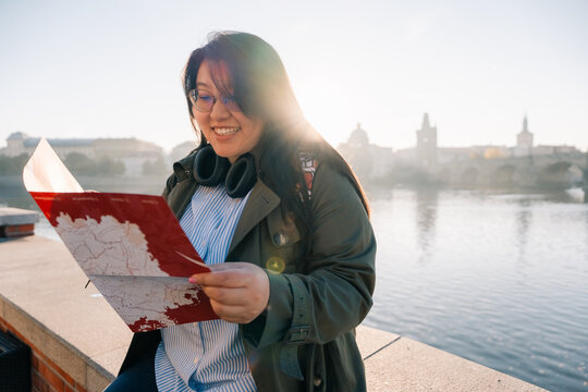 Asian tourist read map while enjoying view of Prague river sunrise
