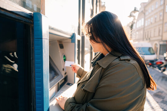 Person using an ATM during the day in urban setting