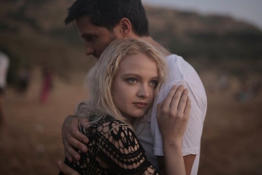 Young couple embracing outdoors with woman looking pensive