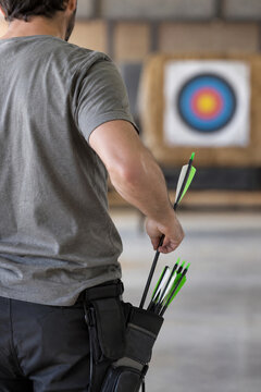 Archer placing an arrow into a hip quiver at an indoor range