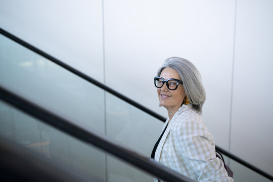 White woman with gray hair on indoor escalator in Madrid, Spain