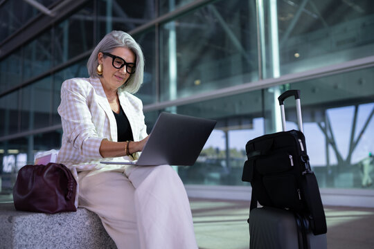 Businesswoman working on laptop with luggage