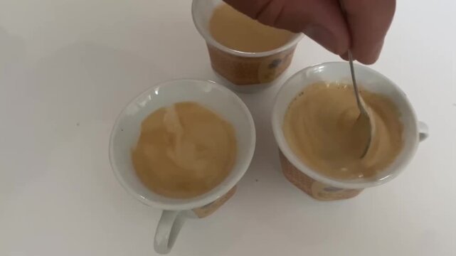 breakfast with hand and spoon mixing three morning coffees