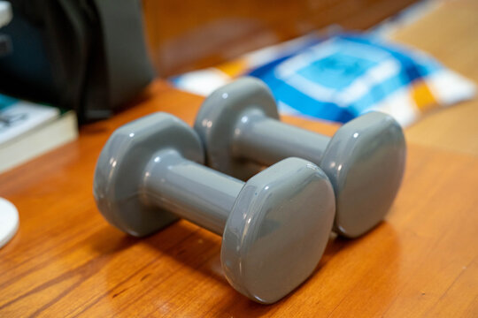 Gray dumbbells placed on a wooden surface, ready for a workout session.