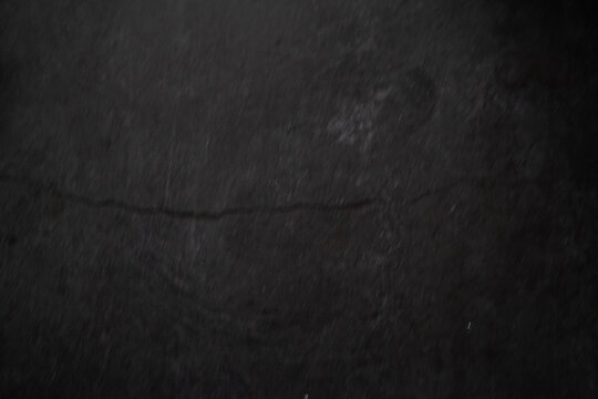 Abstract dark texture with subtle imperfections on a black surface.