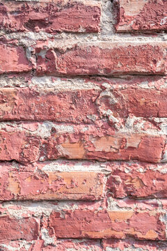 Textured red brick wall with peeling paint, creating a rustic and vintage feel.