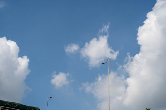 Bright blue sky with fluffy clouds and a lone streetlight in view