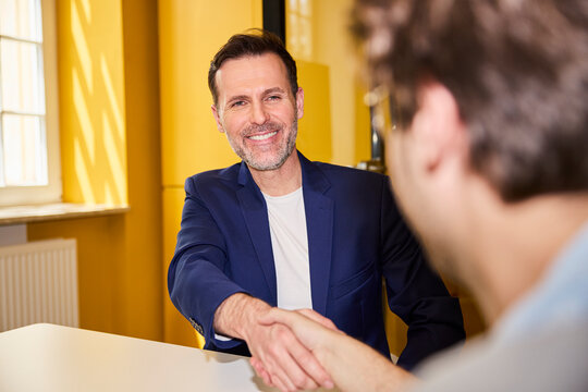 Smiling businessman gives a handshake during an office job interview