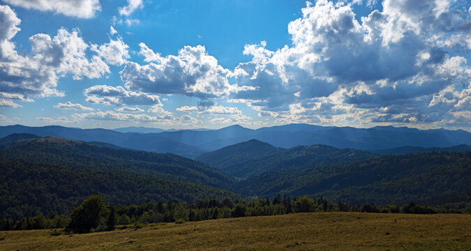 Beautiful summer landscape of green mountain slopes covered with forests under a blue cloudy sky. Epic mountain vista in the Carpathians.
Majestic mountain landscape with layers of hills under dynamic