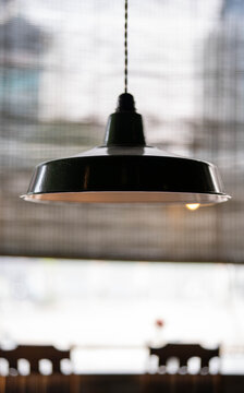 A stylish metal pendant lamp hanging over a cozy caf&eacute; setting.