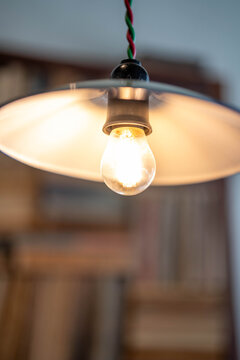 Illuminated vintage light bulb under a modern lampshade.
