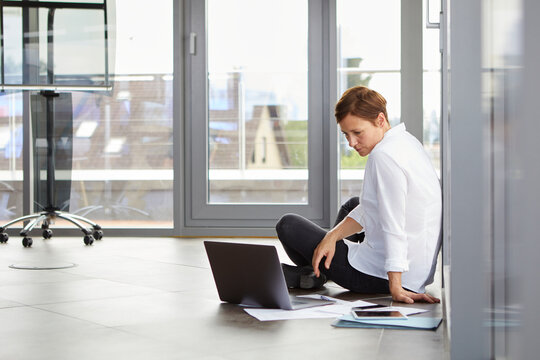 A businesswoman works on her laptop on the office floor