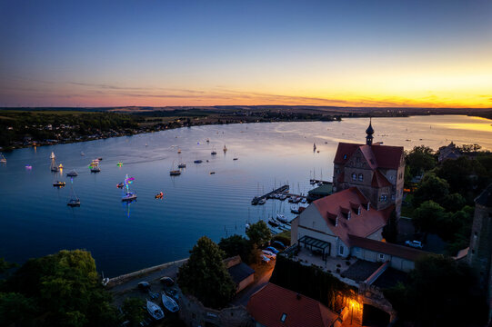 Viele Segelboote auf einem See neben einem Schloss bei Sonnenuntergang