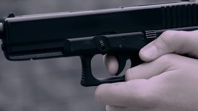 A hand reloads a pistol or cocks the pistol and fires a shot, a close-up of the trigger