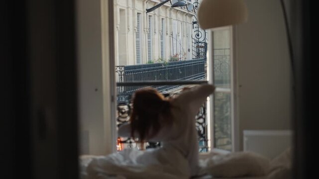 Woman waking up and stretching in a parisian apartment