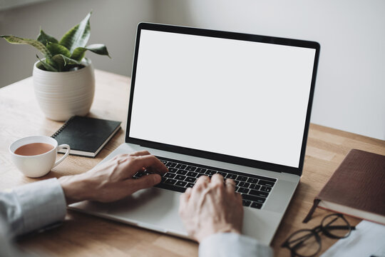 Young man using laptop computer with blank empty mockup screen. Business man working at home. Freelance, student lifestyle, e-learning, shopping online, web site, technology concept