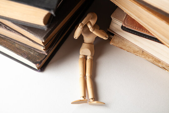 Wooden mannequin sitting on pile of books. Education concept