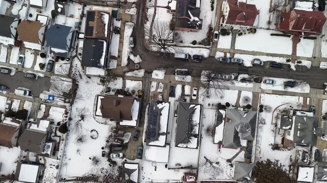 Closely spaced house roofs and small backyards form geometric winter patterns in a top down Queens view.