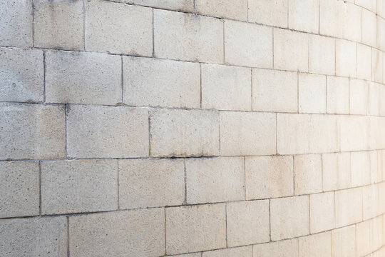Close view of pale concrete block wall with repeating masonry pattern and receding perspective. Industrial construction material texture with copy space for architectural design