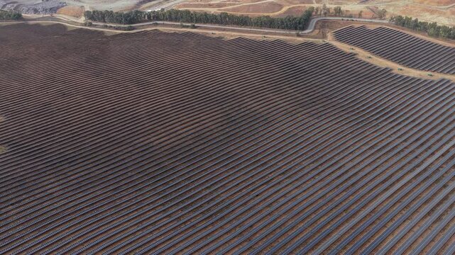 Aerial view of the P.S.F. DON RODRIGO II solar farm, featuring rows of photovoltaic panels across a vast landscape in Alcala de Guadaira, Andalucia, Spain.