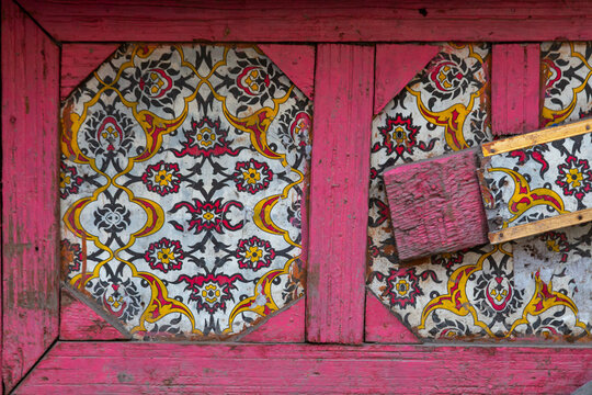Weathered pink wooden door with painted floral pattern panels, Jammu and Kashmir, Srinagar, India